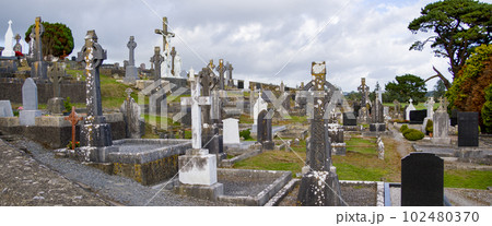 An ancient Christian cemetery in Ireland. Stone tombstones, Celtic cross. Christian cemetery under cloudy sky 102480370
