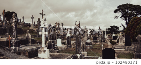 An cemetery in Ireland. Stone tombstones, Celtic cross. Christian cemetery, cloudy sky 102480371
