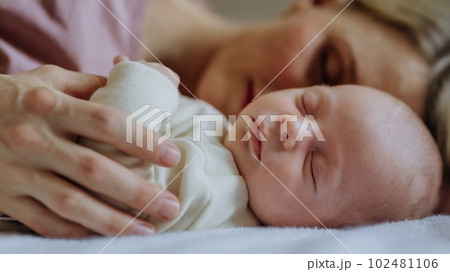 Mother cuddling with her newborn baby in their bed. 102481106
