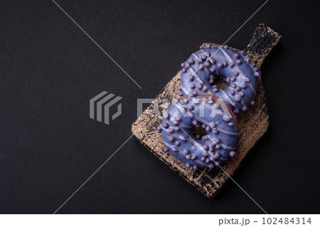 Delicious sweet donut of purple color in glaze and with lilac balls 102484314