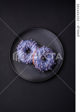 Delicious sweet donut of purple color in glaze and with lilac balls 102484588
