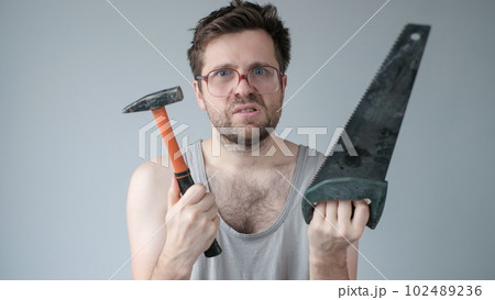 Young caucasian worker man holding a hammer isolated on grey background 102489236