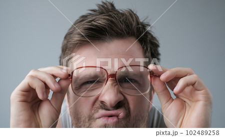 Surprised man in big glasses with WOW expression on gray backgound 102489258