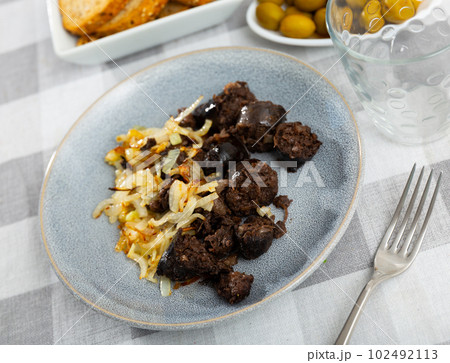 Morcilla con cebolla - fried blood sausage with onion on table Morcilla con cebolla - fried blood sausage with onion on table 102492113