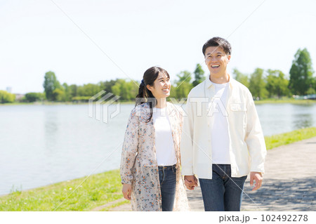 池の畔を歩く男女のポートレート 102492278