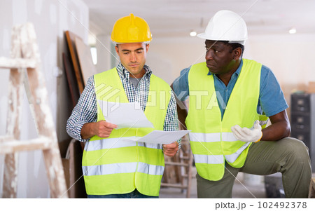 Builders having conversation about work plan in apartment 102492378