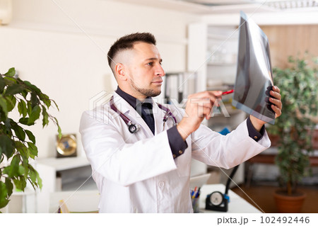 Male doctor examining x-ray at clinic 102492446