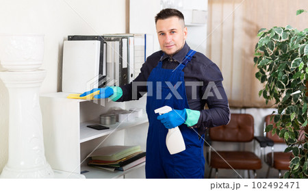 Man wipes dust from table in modern office 102492471