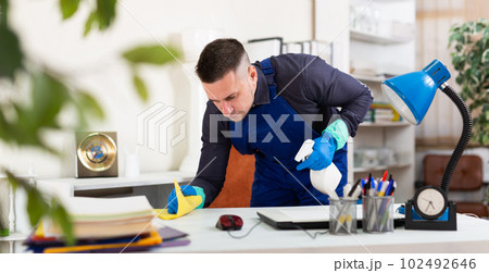 Male cleaner wiping dust from table in office Male cleaner wiping dust from table in office 102492646