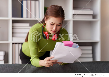 Woman sits on sofa at home, studying and analyze house bills and submitting tax forms. 102495756