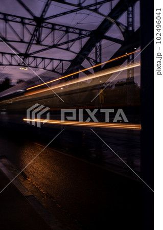 Defocused Lights of cars at night in Krakow bridge. Street line lights. Night highway city. Long exposure photograph night road. Colored bands of red light trails on the road. Background wallpaper  102496041