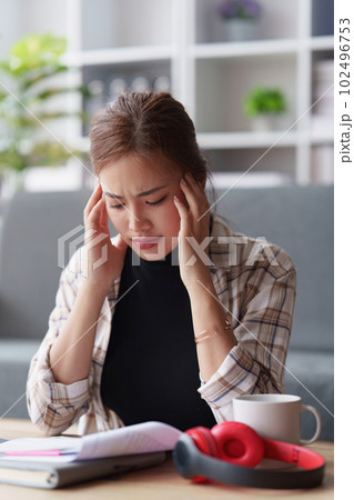 Stressed woman sits on sofa at home, studying and analyze house bills and submitting tax forms. Stressed woman sits on sofa at home, studying and analyze house bills and submitting tax forms. 102496753