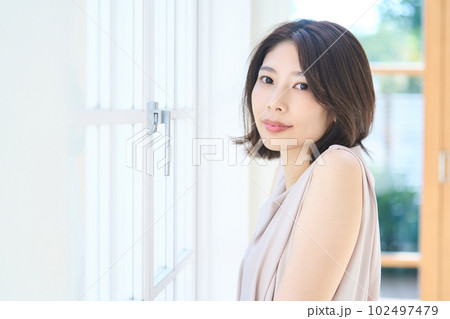 窓際で光を浴びる若い女性 102497479