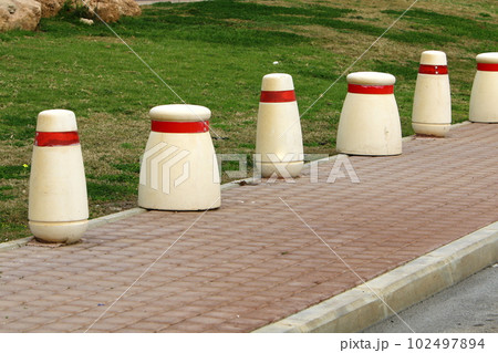 fencing along the road for the safety of pedestrians on the sidewalk 102497894