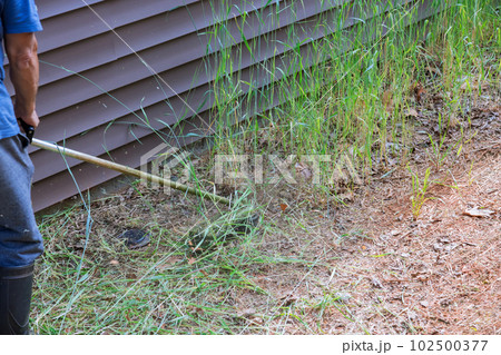 Trimming grass on lawn around residential building with lawn mower is job of worker lawn mower. Trimming grass on lawn around residential building with lawn mower is job of worker lawn mower. 102500377