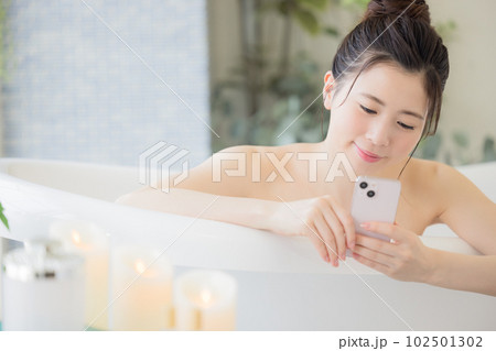 女性　ビューティー　入浴しながらスマホを見る若い女性 102501302