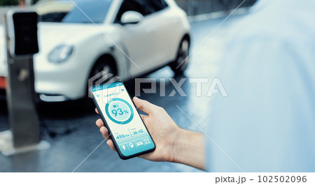 Closeup progressive idea hand holding smart phone display EV's batter status. 102502096