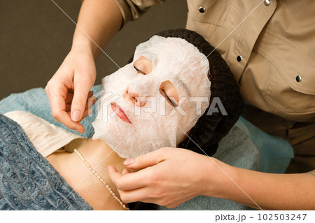 Acne treatment at beautician. Applying sheet mask Acne treatment at beautician. Applying sheet mask 102503247