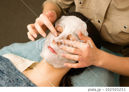 Acne treatment at beautician. Applying sheet mask 102503251