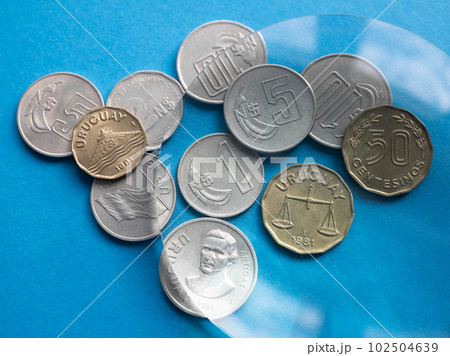 Looking Nuevos Peso and Centesimos coins of Uruguay through a magnifying glass. National Uruguayan currency Looking Nuevos Peso and Centesimos coins of Uruguay through a magnifying glass. National Uruguayan currency 102504639