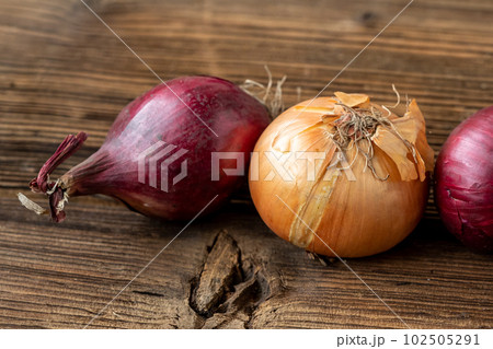 Yellow and red onions on a wooden board 102505291