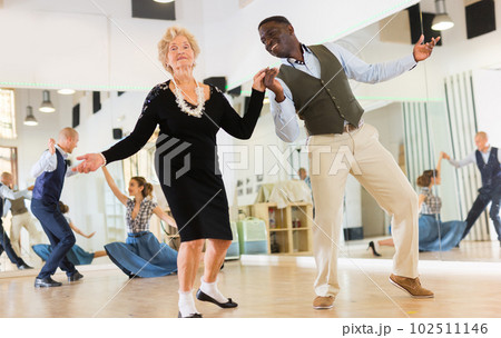 Woman pensioner with african man practising charleston 102511146