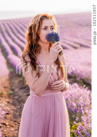 Woman lavender field sunset. Romantic woman walks through the la 102511937