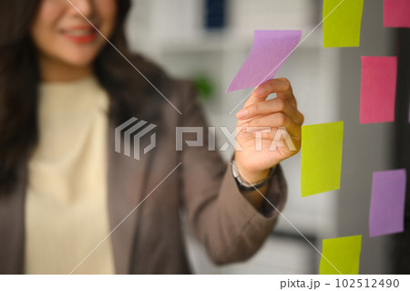 Selective focus on hand. Successful business woman planning tasks on sticky papers or sharing idea for startup project in office 102512490