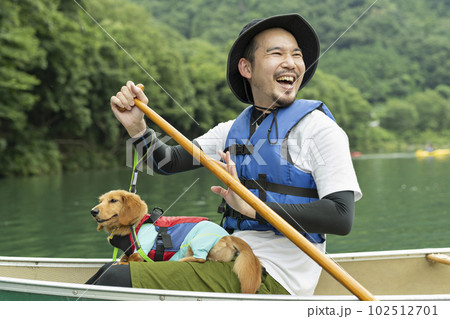 飼い犬と一緒にカヤックで川下りを楽しむ男性 102512701