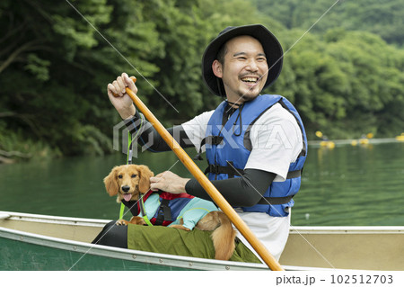 飼い犬と一緒にカヤックで川下りを楽しむ男性 102512703