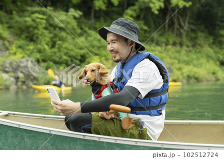 カヤックで飼い犬と一緒に写真を撮る男性 102512724