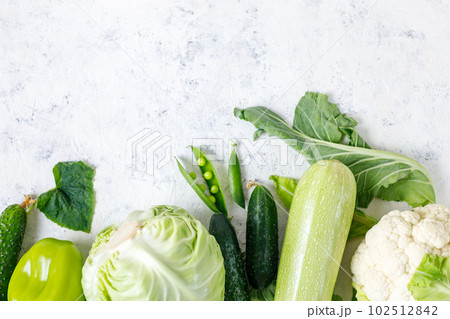 Border of organic green raw vegetables on white table. Top view of healthy organic food. Copy space 102512842