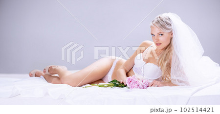Portrait, sexy and bride with lingerie, luxury and happiness against a grey studio background. Face, female person and happy woman with underwear, flowers and honeymoon with joy, bedroom and beauty Portrait, sexy and bride with lingerie, luxury and happiness against a grey studio background. Face, female person and happy woman with underwear, flowers and honeymoon with joy, bedroom and beauty 102514421