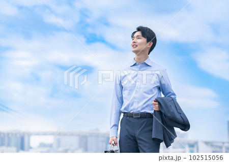 オフジャケットで爽やかに歩く若いビジネスマン 102515056