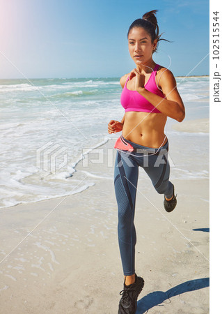 Taking her workout outdoors. an attractive young woman working out on the beach. 102515544