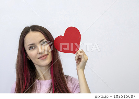 Beautiful girl with a red paper heart on a white background with copy space. Woman in pink. Valentine's Day, February 14 Beautiful girl with a red paper heart on a white background with copy space. Woman in pink. Valentine's Day, February 14 102515687