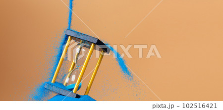 Hourglass is money sand of time, business pouring blue sand into hourglass to add more time in financial. Deadline extended time management hope concept to gold hour glass. Orange background sunset 102516421