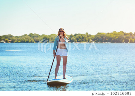 This is my kinda adventure. an attractive young woman paddle boarding on a lake. 102516695