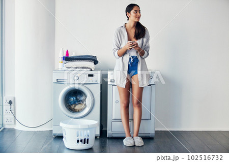 Checking the rest of my to-do list. a young attractive woman doing her laundry at home. Checking the rest of my to-do list. a young attractive woman doing her laundry at home. 102516732