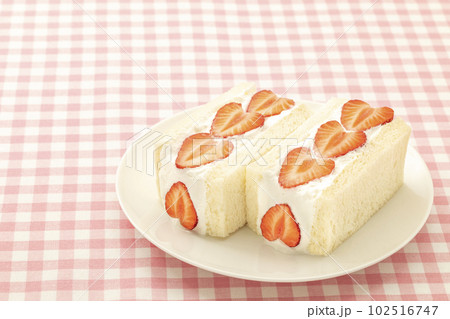 白い丸皿に置いたイチゴのフルーツサンド 102516747