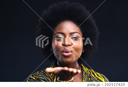 Sending some love your way. a young woman blowing a kiss against a dark background. 102517420