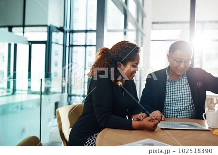Discussing ways to profit from all their top ideas. two businesspeople going through some paperwork in an office. 102518390