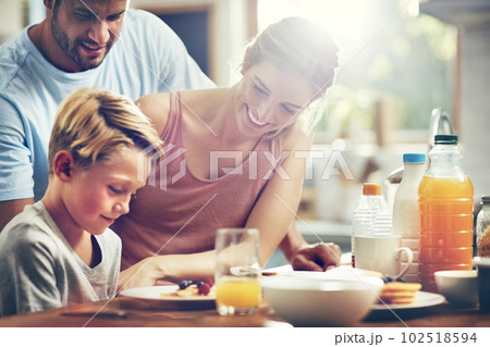 Theres no way hell say no to pancakes. a little boy eating breakfast with his parents. 102518594