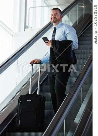 Visiting clients all over the world. a businessman traveling down an escalator in an airport. Visiting clients all over the world. a businessman traveling down an escalator in an airport. 102520519