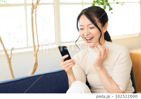 スマホを片手に考え中のミドル女性 102522000