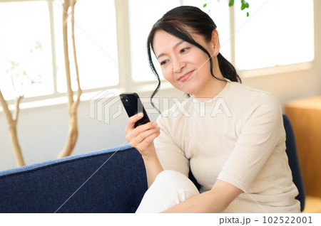 スマホを片手に考え中のミドル女性 スマホを片手に考え中のミドル女性 102522001