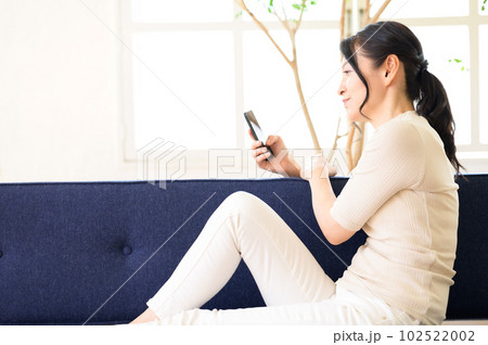スマホを片手に考え中のミドル女性 102522002