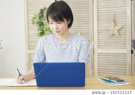 リビングでノートパソコンを使って勉強する女性 リビングでノートパソコンを使って勉強する女性 102523137