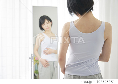鏡の前でお腹の贅肉を気にする女性 102523151