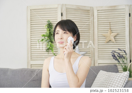 自宅で美顔器でフェイシャルケアをする女性 自宅で美顔器でフェイシャルケアをする女性 102523158